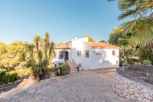 a white house with palm trees and a stone driveway at El Refugio - Quite and Spacious in Benissa