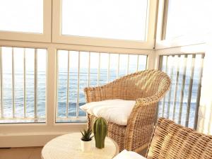 a wicker chair and table in a room with windows at Piso en el Mar in Salinas