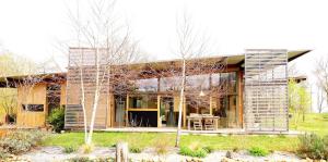 a house with wooden walls and windows and some trees at Gite Dilos in Gan