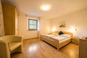 a bedroom with a bed and a chair in it at Stettnerhof Wohnung Laugen in Vollan