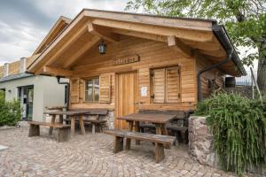 a wooden building with picnic tables and benches at Stettnerhof Wohnung Laugen in Vollan
