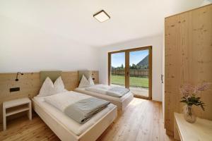 a bedroom with two beds and a large window at Masi Rosmarin in Santa Valpurga