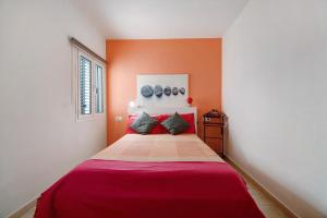 a bedroom with a large bed with orange walls at Apartamento Caepionis in Chipiona +13 photos