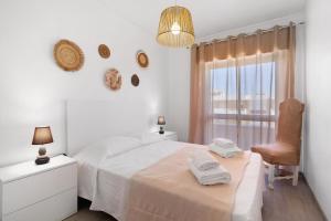 a white bedroom with a bed and a chair and a window at Justo's House in Faro