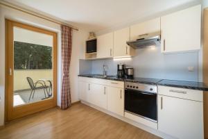 a kitchen with white cabinets and a stove top oven at Ferienhaus Maria Edelweiss in Moso +13 photos