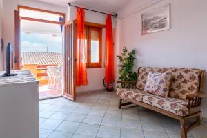 a living room with a couch and a window at House Leoni in Isola Rossa