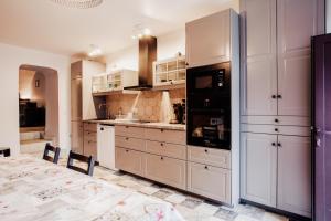 a large kitchen with white cabinets and a table at Maison Conviviale 3 Vallées in Novallay