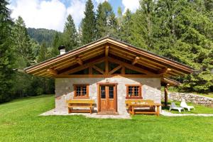a small cabin with a table and benches in the grass at Baita Valon - Alpine Hideaway in Comano Terme