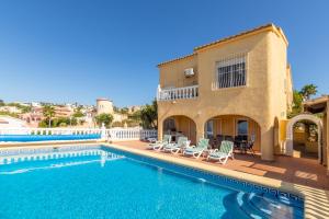 a swimming pool with chairs and a house at Casa Maravilla in Benitachell