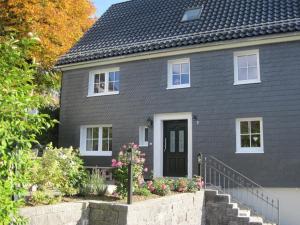 a gray house with a black door and some flowers at Haus Lindenfürst in Olsberg