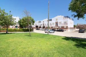 a large white building with cars parked in a parking lot at Quinta Gomeira 69 in Cabanas de Tavira