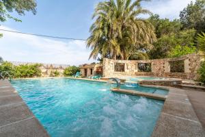 an outdoor swimming pool with a stone building and trees at La Carrasca - Limón in Catral