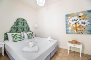 a bedroom with a white bed with a painting on the wall at M1 room in Nikiana