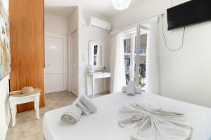a white bedroom with a white bed and a television at M1 room in Nikiana