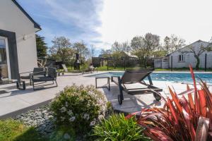 a patio with a glass table and chairs next to a swimming pool at Maison Ty Rhuys avec piscine in Saint-Gildas-de-Rhuys