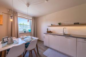 a kitchen with white cabinets and a table with chairs at Ferienwohnung Julia in Taching am See