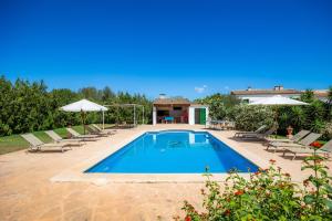 a pool with chairs and umbrellas next to a house at Na Amera Ref 225 in Campos