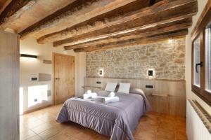 a bedroom with a bed and a stone wall at Cal Trumfet in Caserras +37 photos