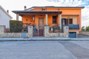 a orange house with a stone fence in front of it at Casa Vacanze vicino ad alghero in Olmedo