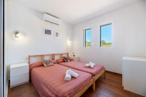 two beds in a room with white walls and windows at Es Camp in Cala Saona