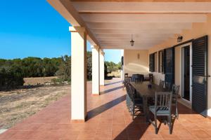 a porch with a wooden table and chairs on it at Es Camp in Cala Saona