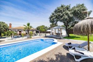a swimming pool with chairs and a house at Villa mis Raices in Castilblanco de los Arroyos