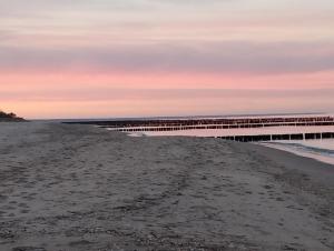 a pier stretches out over the beach at sunset at Haus Arvert in Koserow