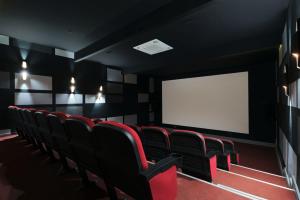 a cinema room with red chairs and a white screen at Athena Premium Suites in Erdemli