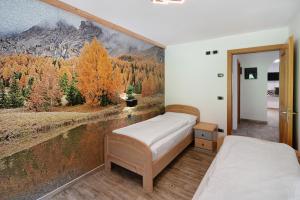 a bedroom with two beds and a painting on the wall at Ciasa Badia in Pozza di Fassa