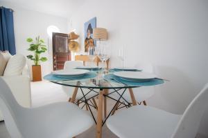 a dining room with a glass table and white chairs at Beach And Mountain Apartment in Sesimbra