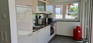 a kitchen with white cabinets and a window at Alpenblick 1 in Lindau-Bodolz