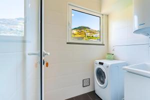 a laundry room with a washing machine and a window at Casa Sol in Caniço