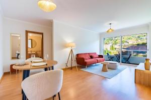 a living room with a table and a red couch at Casa Sol in Caniço