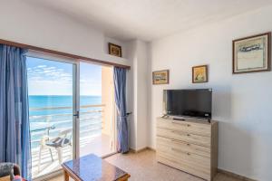 a living room with a tv and a large window at Calpe primera linea con piscina in Casas de Torrat