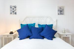 a white bed with blue pillows on it at Salitre in Playa Honda