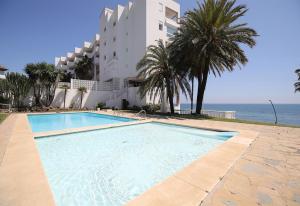 a swimming pool in front of a building and the ocean at Apartment Boulevard 105 in Estepona
