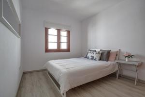 a white bedroom with a bed and a window at Casa Ann in Arrecife