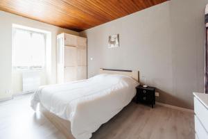 a bedroom with a white bed with a wooden ceiling at Gîte Zen Attitude in Saint-Martin-sur-le-Chambre