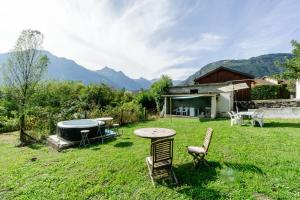 a backyard with a table and chairs and a hot tub at Gîte Zen Attitude in Saint-Martin-sur-le-Chambre