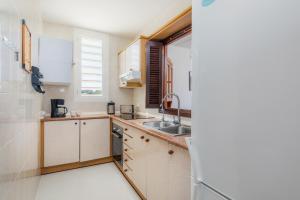 a kitchen with white cabinets and a sink and a window at Casa Laura in Cala Ratjada
