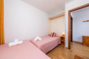 two beds in a room with pink sheets at Casa Laura in Cala Ratjada