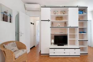 a living room with a tv and a white book shelf at Beach Paradise - Cicerone in Levanto
