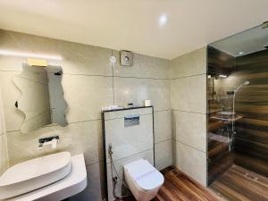 a bathroom with a toilet and a sink and a shower at Hotel Kama, Patna in Patna +2 photos