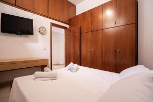 a bedroom with a bed with wooden cabinets and a tv at Villa Nikolaos in Rhodes Town