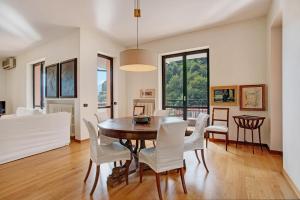 a dining room with a table and white chairs at Appartamento Il Parco Cernobbio in Cernobbio