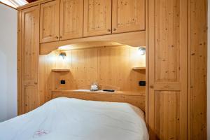a bedroom with wooden cabinets and a white bed at Emma Home in Mezzolombardo