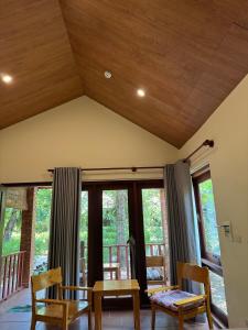 a living room with a table and chairs and windows at Wildland Resort in Phú Quốc