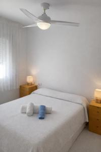 a bedroom with a white bed with a blue towel on it at Tramuntana apart in Calafell