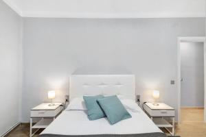 a bedroom with a white bed with blue pillows at Alfons I in Puigcerdà