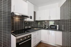 a kitchen with white cabinets and black appliances at Hanna's Sunny Apartment in Albufeira +26 photos